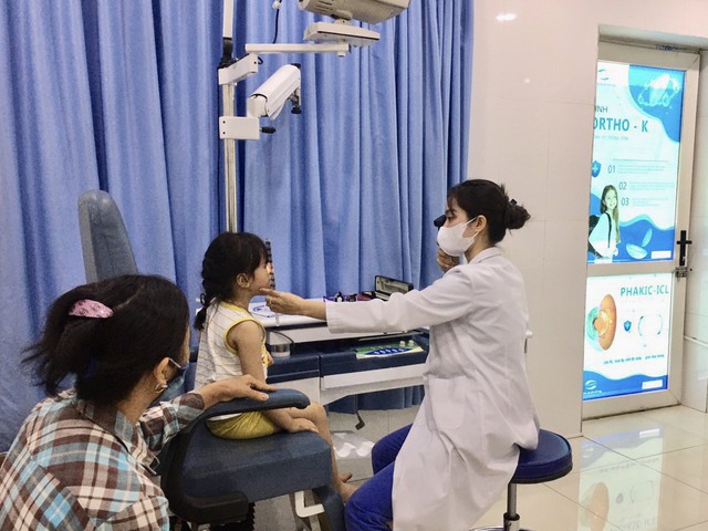 Cử nhân khúc xạ nhãn khoa Nguyễn Thị Huyền đang soi bóng đồng tử cho trẻ